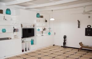 a living room with white shelves and a flat screen tv at Umoja Guesthouse II in Ouagadougou