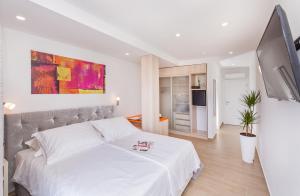 a bedroom with a large white bed and a tv at Boutique Flamingo B&B in Mlini