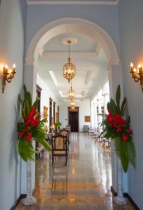 a hallway with red flowers and a dining room at Casa Azul Monumento Historico in Mérida