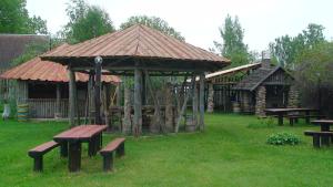 a pavilion with picnic tables and benches in a park at TammeKännu Kämpingud in Mammaste