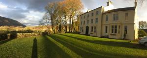 a large white house on a grassy yard at Bonawe House Holiday Cottages in Taynuilt