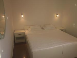 a small bedroom with a white bed with two pillows at Apartments Danilo Kažanegra in Sveti Stefan