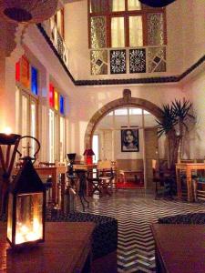 a room with an arch in a building with tables and chairs at Jennat El Mossafir-Riad privé avec services in Essaouira