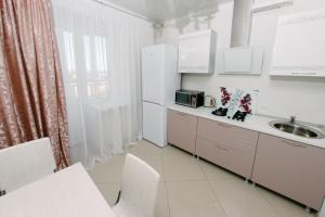 a white kitchen with a sink and a refrigerator at City Center Apartment on Pochtovy 4 in Orenburg