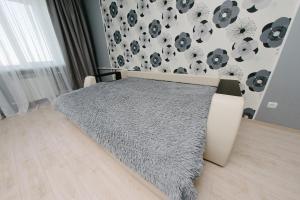 a bedroom with a bed with a gray comforter at City Center Apartment on Pochtovy 4 in Orenburg