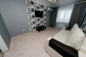 a living room with a white couch and a tv at City Center Apartment on Pochtovy 4 in Orenburg