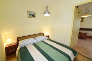 a bedroom with a bed with a green and white blanket at Apartments Galic in Rab