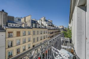 uma varanda de um edifício com cadeiras e edifícios em Le A em Paris