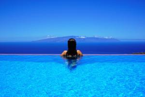 a woman sitting in a swimming pool looking out at the ocean at Finca Stemann in Guía de Isora