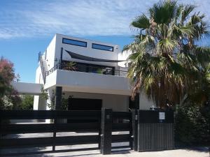 a white house with a fence and a palm tree at Appartement rdc pieds dans l'eau in Sète