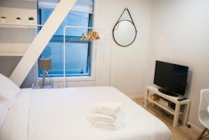 een witte slaapkamer met een bed en een televisie bij Snug Studio in the heart of the city in Auckland