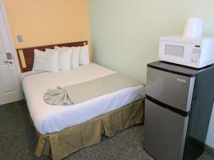 a hotel room with a bed with a microwave on a refrigerator at Key West Hotel in Wildwood