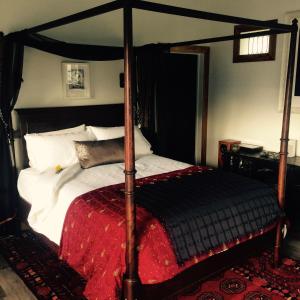 Marriner's Boutique Guesthouses في Rawene: غرفة نوم مع سرير مظلة مع بطانية حمراء