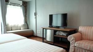a room with a tv and a couch and a chair at The Brown House Hotel in Chachoengsao