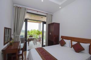 a bedroom with a bed and a desk and a balcony at Hoi An Sun Lake Villa in Hoi An