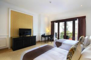 a hotel room with two beds and a flat screen tv at Grand Palace Hotel Sanur - Bali in Sanur