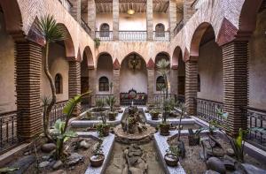 Hotel Kasbah Le Mirage & Spa في مراكش: ساحة بها نافورة ونباتات في مبنى