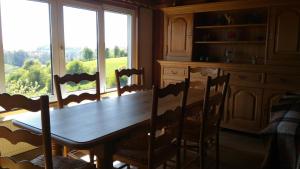 a dining room table with chairs and a large window at Gite des 3 bouleaux in Robelmont