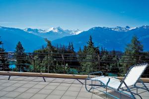 a pair of chairs sitting on a balcony overlooking mountains at Crans-Montana Youth Hostel in Crans-Montana