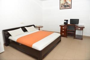 a bedroom with a bed and a desk and a television at Hotel Novela Star in Lomé +24 photos