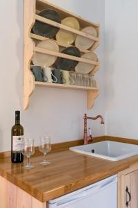 a kitchen with a sink and a shelf with wine glasses at Asymi Residences in Symi