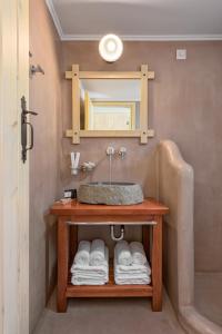ein Badezimmer mit einem Waschbecken, einem Spiegel und Handtüchern in der Unterkunft Asymi Residences in Symi