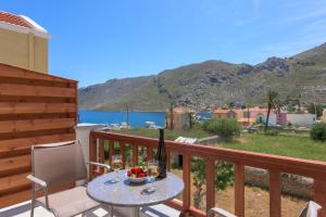 a table with a bottle of wine and a bowl of fruit on a balcony at Asymi Residences in Symi