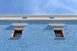 two windows on the side of a blue building at Asymi Residences in Symi
