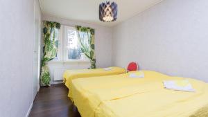 2 letti in una camera con lenzuola gialle e finestra di Tiinan tupa A a Moksinkylä