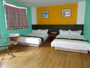花蓮市的住宿－微風民宿，酒店客房带两张床和一张桌子以及椅子。