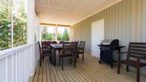 un portico con tavolo, sedie e griglia di Tiinan tupa B a Moksinkylä