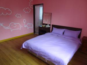 花蓮市的住宿－微風民宿，一间卧室配有一张床和粉红色的墙壁