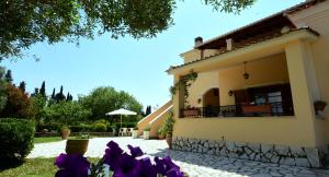una casa con fiori viola nel cortile di Villa Rose Garden ad Ágios Ioánnis