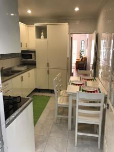een keuken met witte kasten en een tafel en stoelen bij Casa da Ponte Amarela in Aveiro