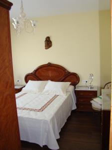 a bedroom with a large bed with a wooden headboard at Apartamento Pedras in Vilagarcia de Arousa