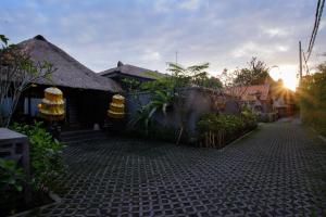 una casa con techo de paja y entrada de ladrillo en Ubud Wana Villa, en Ubud