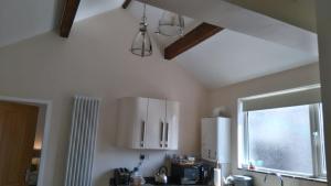 a kitchen with white cabinets and a window at Canterbury Cottage in Prestatyn