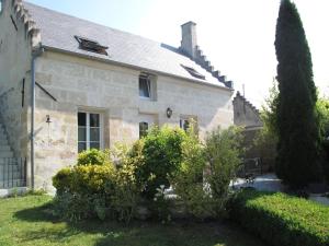 een stenen huis met struiken ervoor bij La Maison Des Chiens Rouges in Berneuil-sur-Aisne