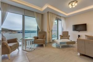 a living room with a tv and a couch and chairs at Paris Residence Cesme in Cesme