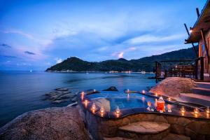 a swimming pool next to the ocean at night at Panviman Resort Koh Phangan - SHA Extra Plus in Thong Nai Pan Noi
