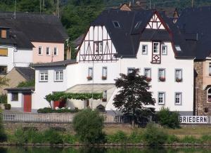 a large white building with a black roof at Pension Mosellablick in Briedern