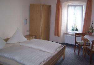 a bedroom with a bed and a table and a window at Pension Mosellablick in Briedern