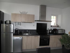 a kitchen with wooden cabinets and a stainless steel refrigerator at La Maison Des Chiens Rouges in Berneuil-sur-Aisne +3 photos