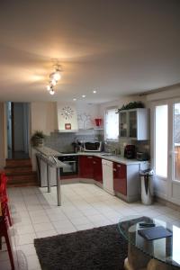 une grande cuisine avec des placards rouges et une table dans l'établissement Gîte Villa Louis Victor, à Villers-sous-Châtillon