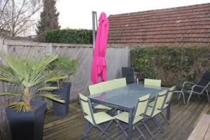 une table avec des chaises et un parasol rose sur une terrasse dans l'établissement Gîte Villa Louis Victor, à Villers-sous-Châtillon