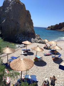 un grupo de sombrillas y sillas en una playa en Psaros Melinta, en Plomari