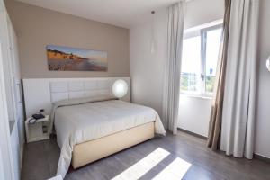 a white bedroom with a bed and a window at Motel S.16 in Muro Leccese