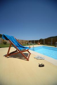 a chair and pair of glasses next to a swimming pool at Aselinos Suites in Koukounaries