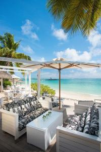 a beach with white chairs and an umbrella and the ocean at Constance Belle Mare Plage in Belle Mare
