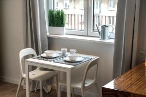 uma mesa branca e cadeiras num quarto com uma janela em Apartament przy Rotundzie em Varsóvia